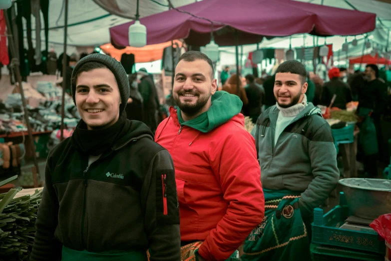 two men and one woman standing in an open air market