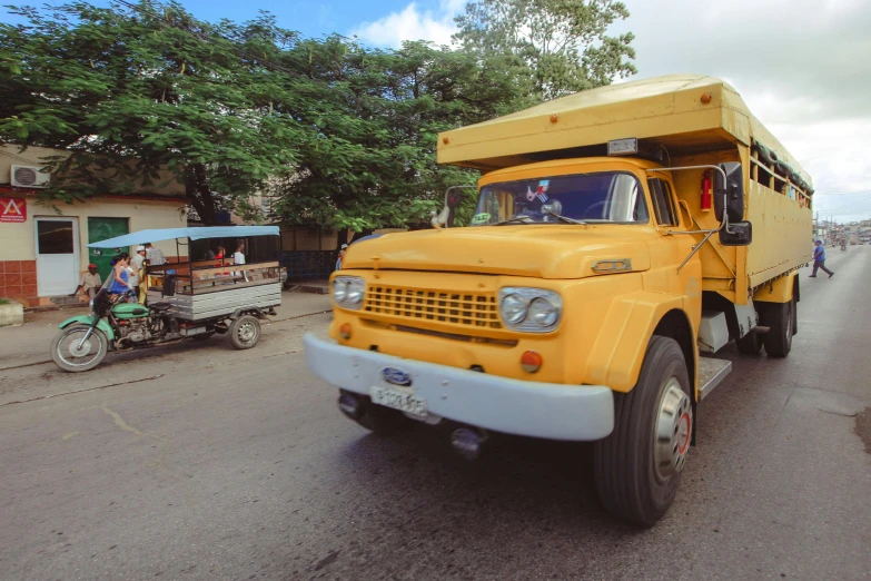 yellow trucks driving down the road near people