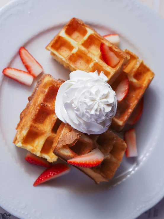 a plate topped with waffles, strawberries and whipped cream