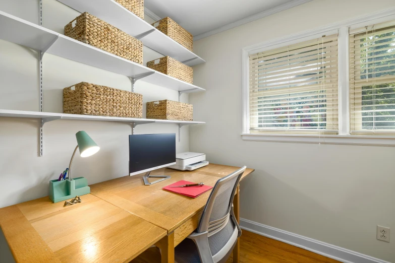 the small desk is next to a large open book shelf