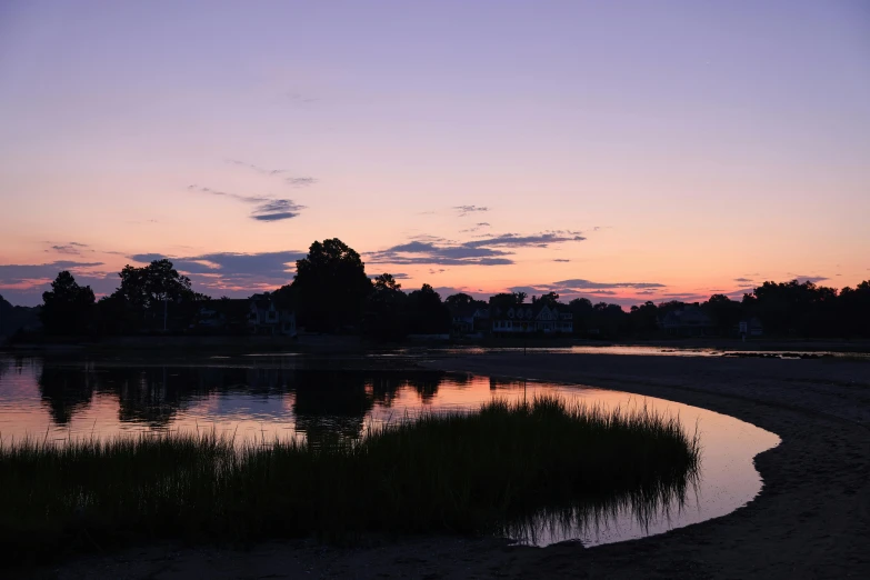 the water is calm and reflecting the sky at sunset