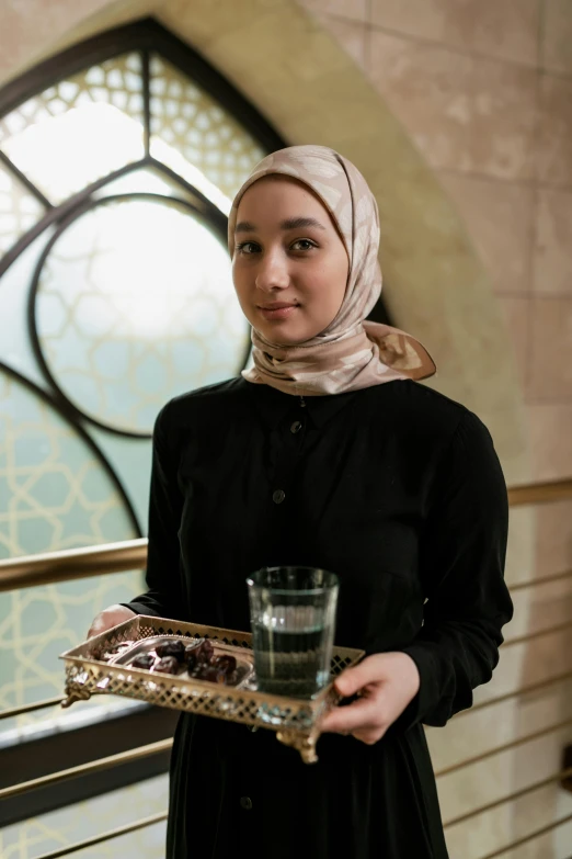 a woman standing holding a tray and a glass of water