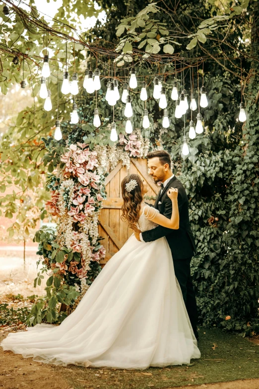 bride and groom kiss underneath a backdrop covered with flowers