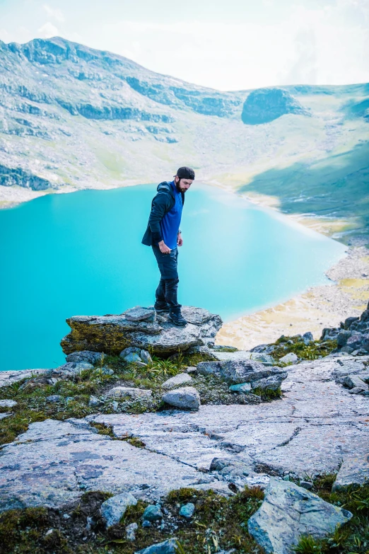 man on top of large rock looking at water