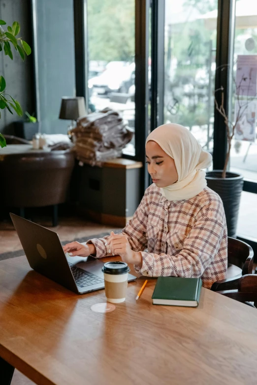 a woman sitting at a table using her laptop