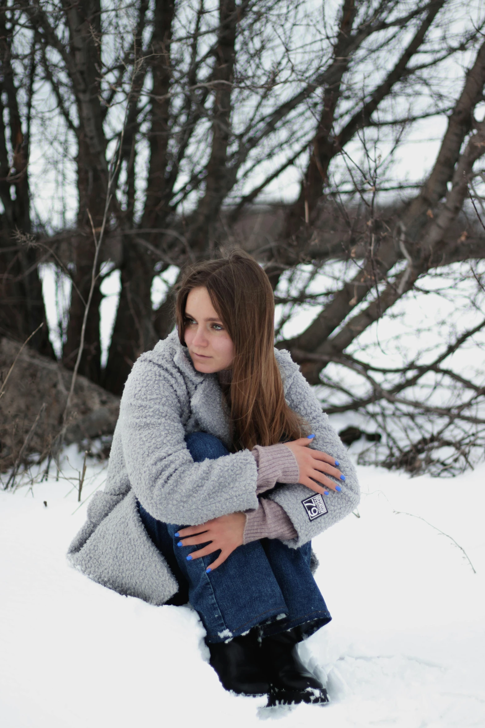 a girl sitting in the snow with her arms folded