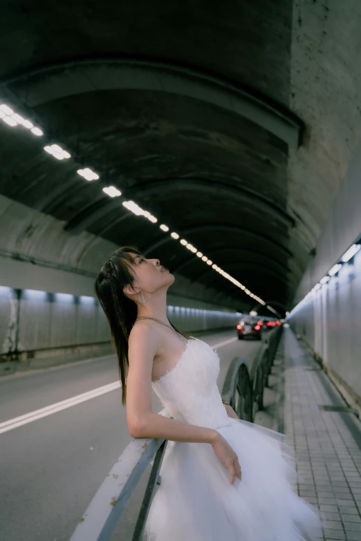 a  wearing a white dress standing in the middle of a tunnel