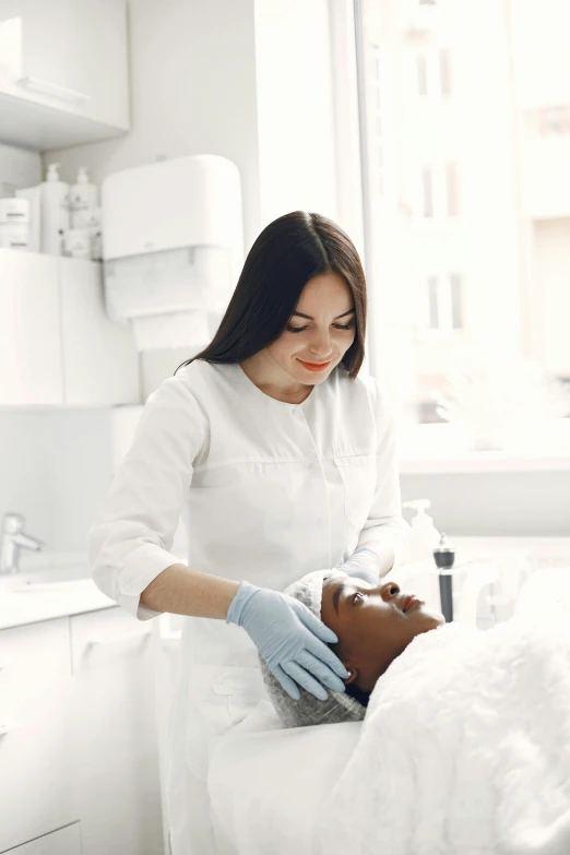 a woman in white dress getting treatment from a person