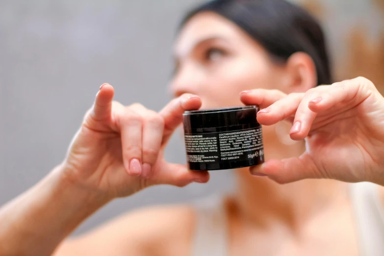 a woman holding a jar of skin cream in her hand