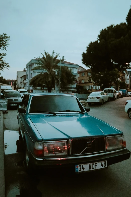 the front of an old blue car parked on a city street