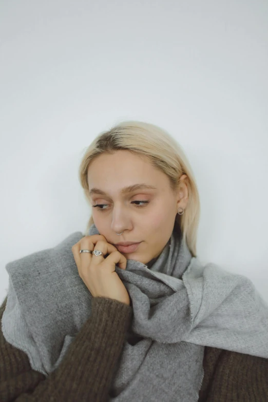 a blonde woman in a grey sweater looking up at the ground