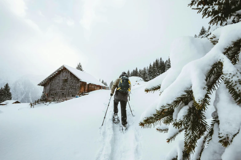 a skier is heading down the slope to the cabin