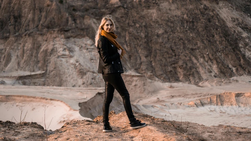 a woman in black top posing on hill next to mountain