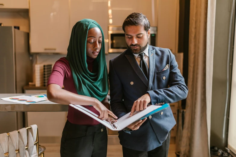 two people in a kitchen making soing on a binder