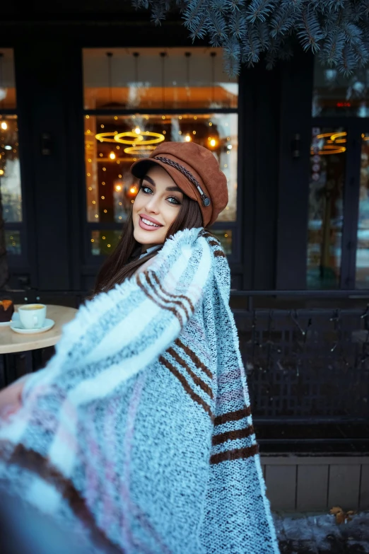 the woman smiles while wearing a ponched shawl