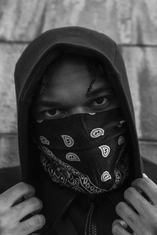 a person wearing a black hoodie with a bandanna around their face