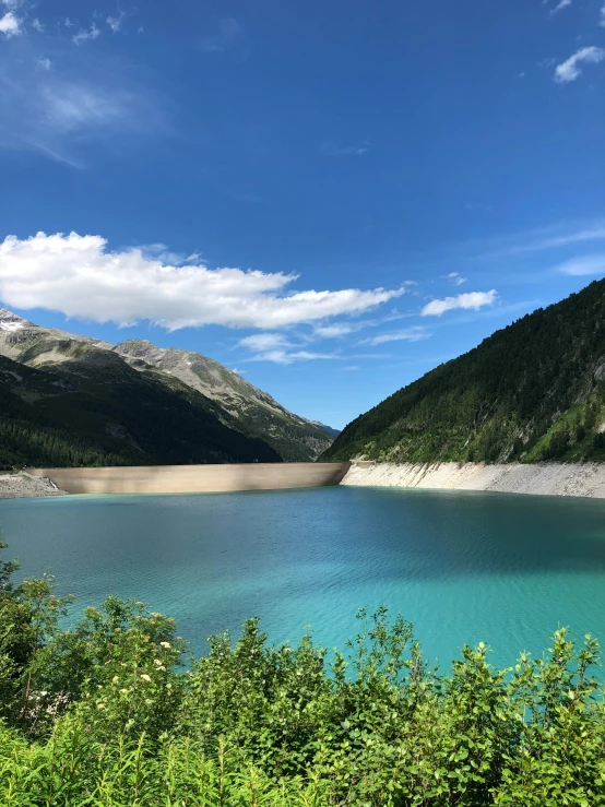 a lake surrounded by mountains and grass