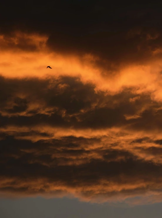 an airplane flying at sunset against a stormy sky