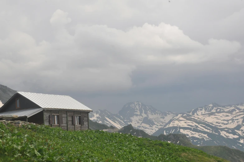 a barn on the hill has a mountain in the back