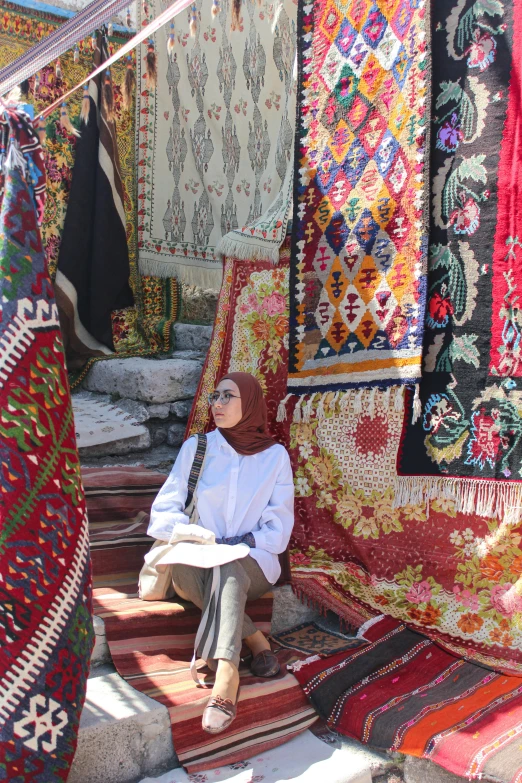 a woman sitting on a patchwork rug outside