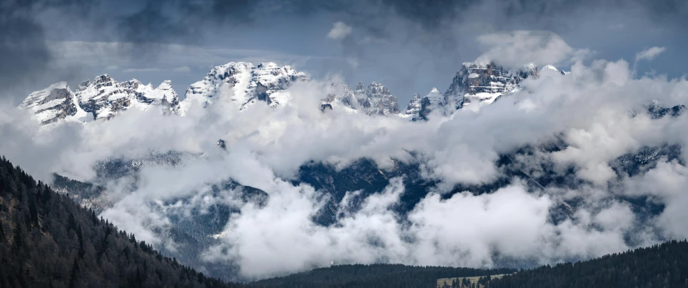 clouds hovers around the top of a mountain range