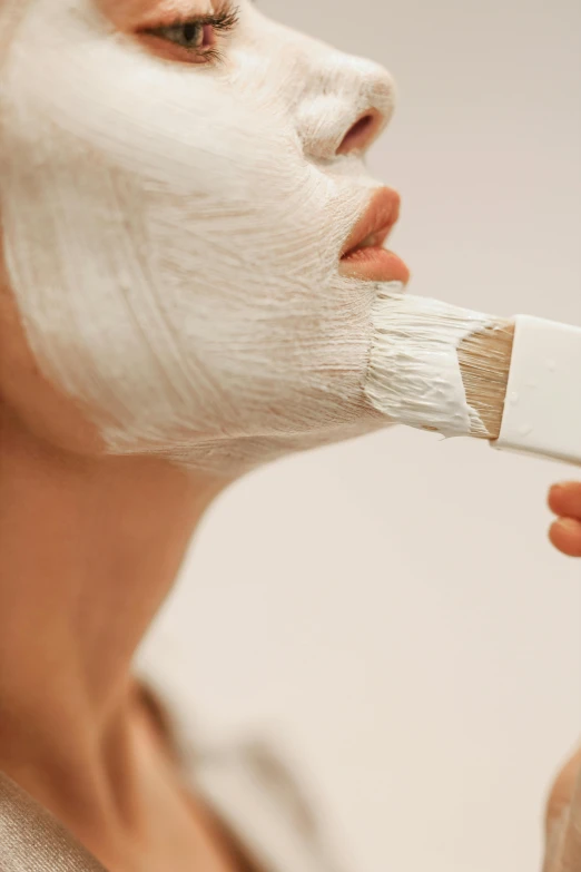 a woman holding a paint brush to her face