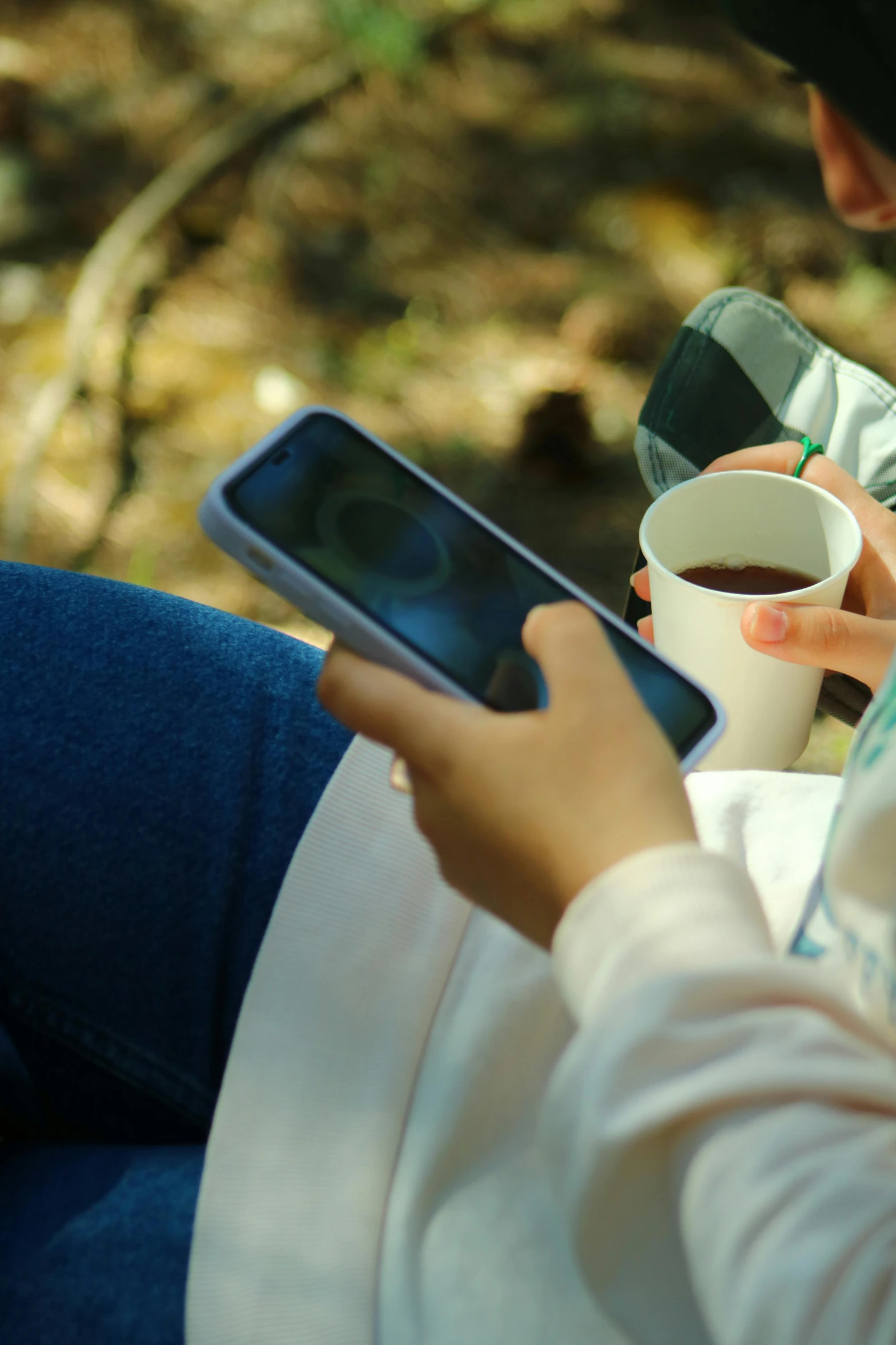 the person is holding a phone and holding a cup of coffee