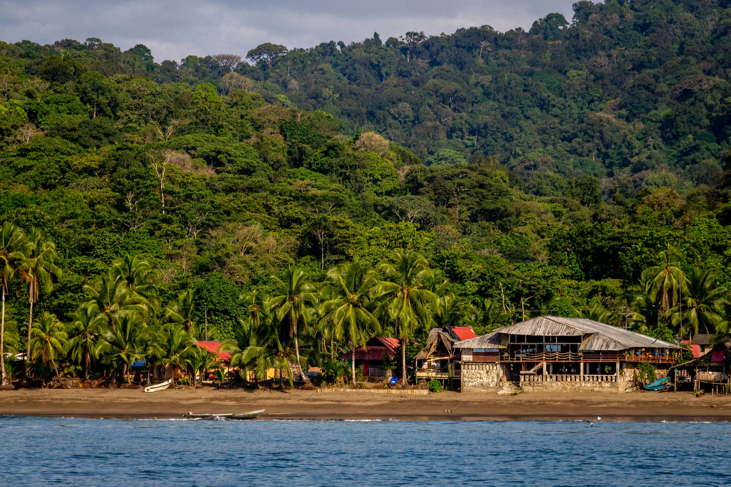 a small hut is built on the shore of a tropical lake