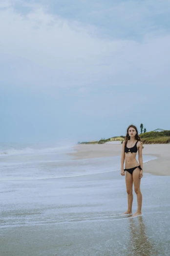a woman in a bikini standing in shallow water