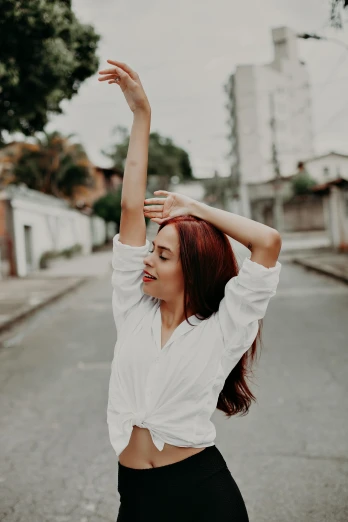 a girl wearing a white top with her arms up