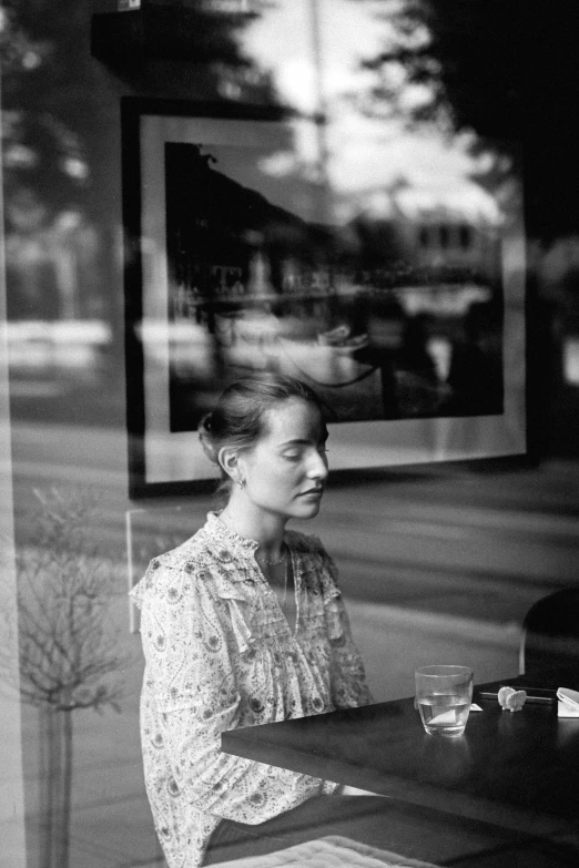 a woman sitting at a table in front of a window