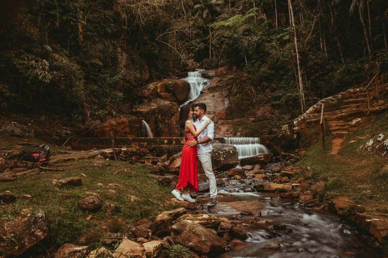 a woman and man stand by a small waterfall