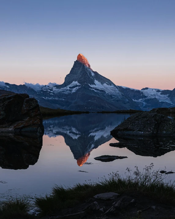 a mountain rising high above the sky near a lake