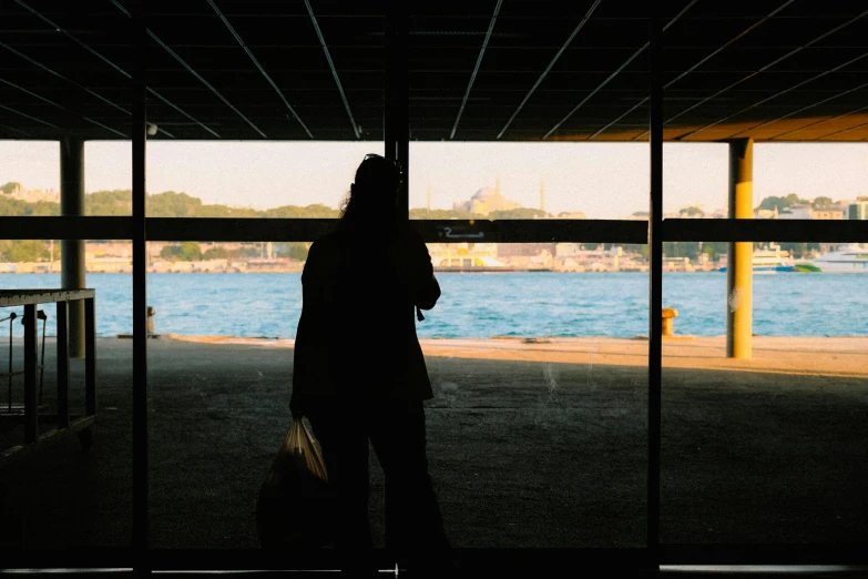 a woman standing in an open covered walkway with a luggage bag