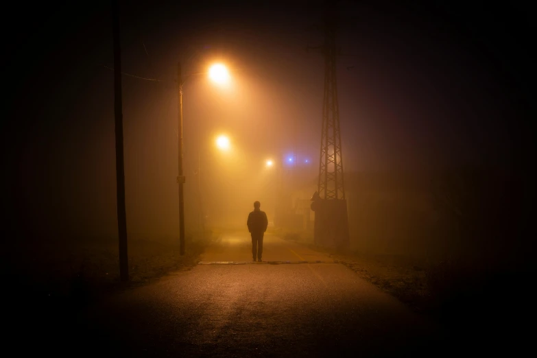 a person walking on a street at night in a foggy area
