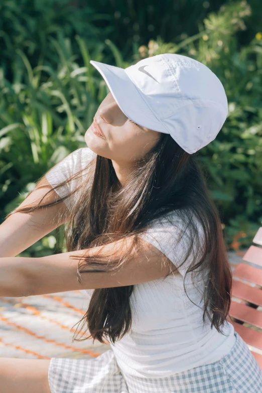 a young woman wearing a hat sitting on a wooden bench