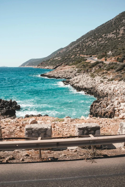 a road that leads to the ocean next to a rocky shore