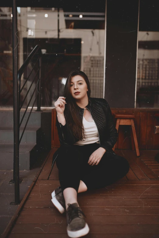 a woman in black jacket sitting on top of a wooden floor