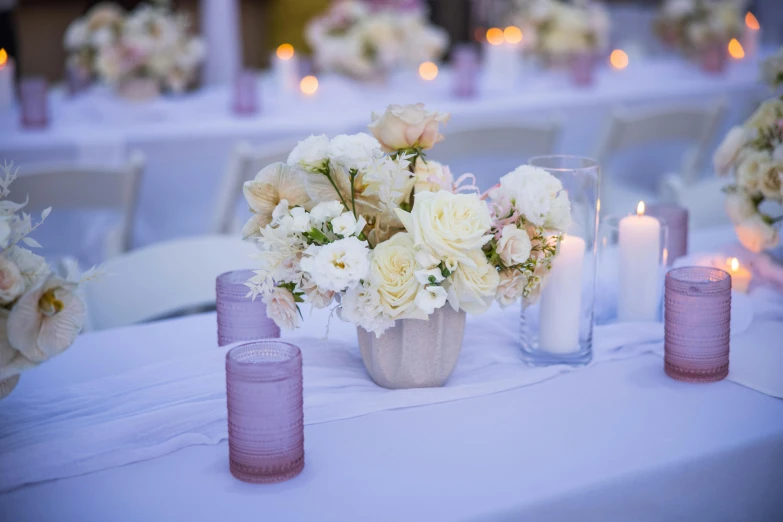 a white table with pink candle holders and flowers on it