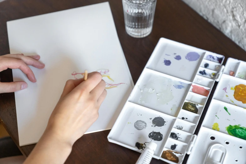 a person painting on a table next to paint