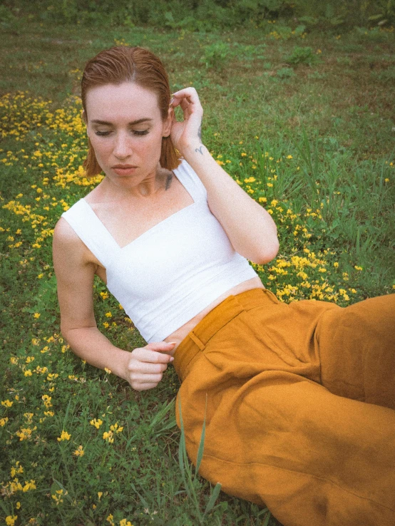 a woman is lying in a flowered field with her foot on a ground