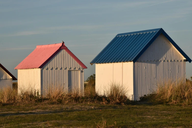 two buildings in a field and one has a red roof