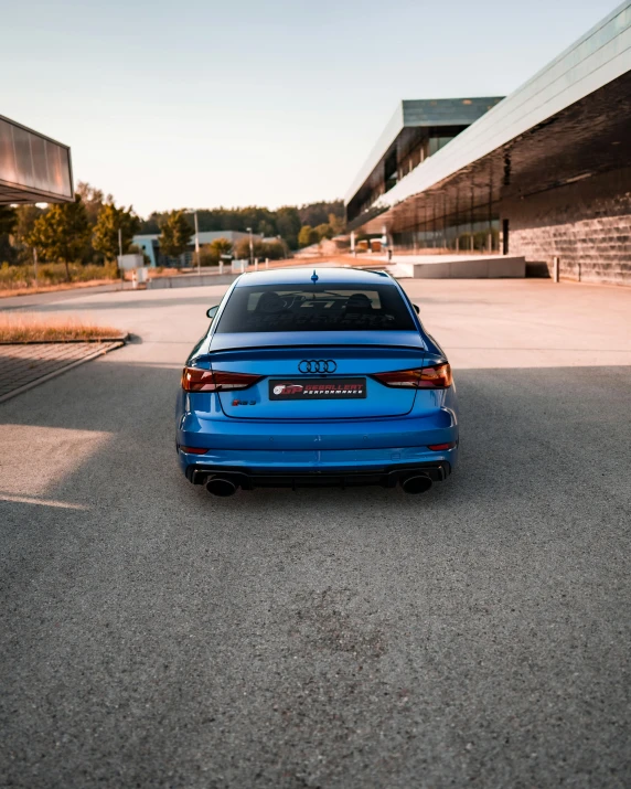 an empty blue car sits in front of a building