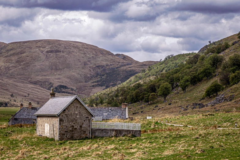 a small, stone building sitting in the middle of a grassy field