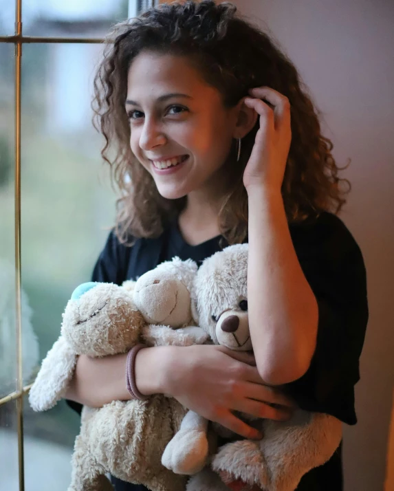 a woman holding two teddy bears in her hands