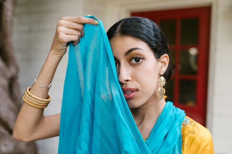 a woman in a blue scarf holding up soing