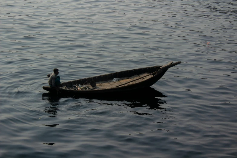 a man sitting in a small wooden boat on the water