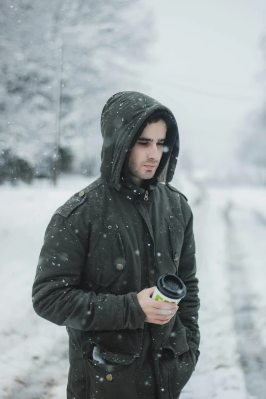 a man in the snow looking down at his cell phone