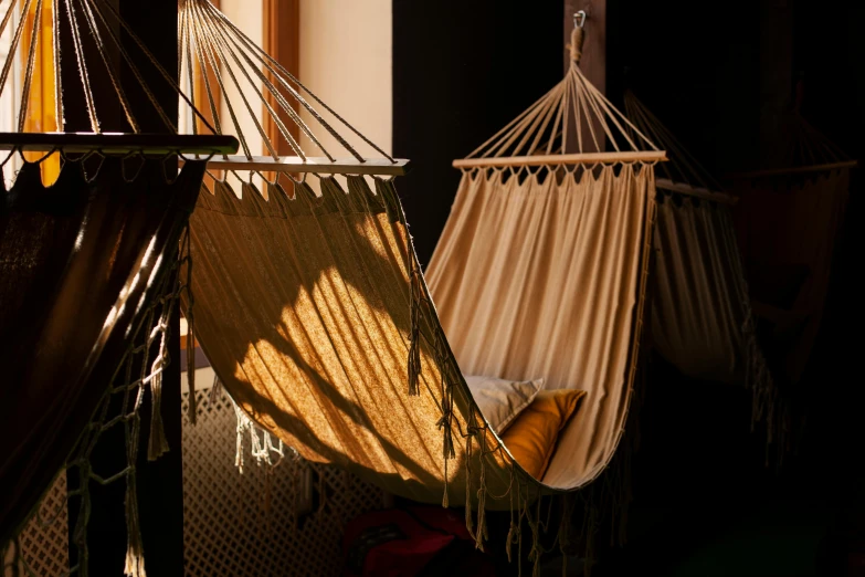 two hammocks hanging in a room near windows