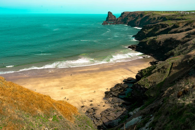 a beach at the edge of a cliff with a large cliff by the beach